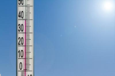 A thermometer reading about 35°C with a clear blue sky and bright sun in the background, indicating a hot, sunny day.